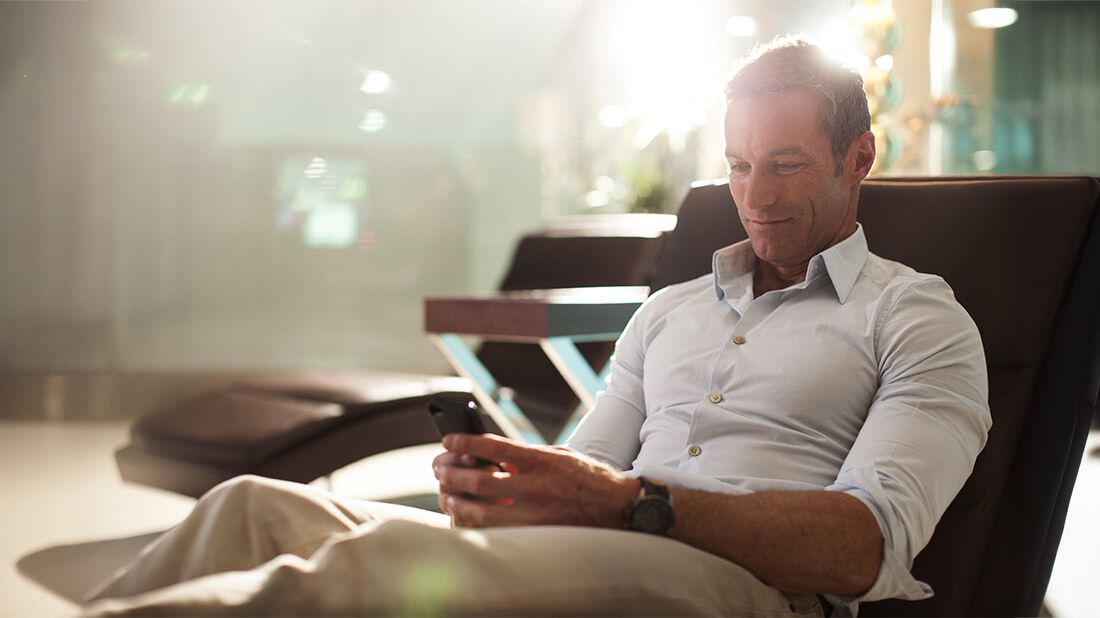 A man using his phone sitting on a lounge chair