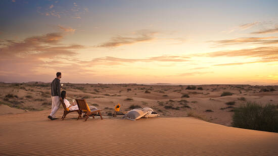 a couple having drinks at a cozy desert setup in the desert