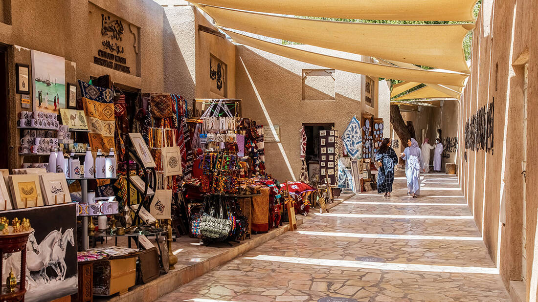 Two women walking past stalls at the Al Fahidi Souk 