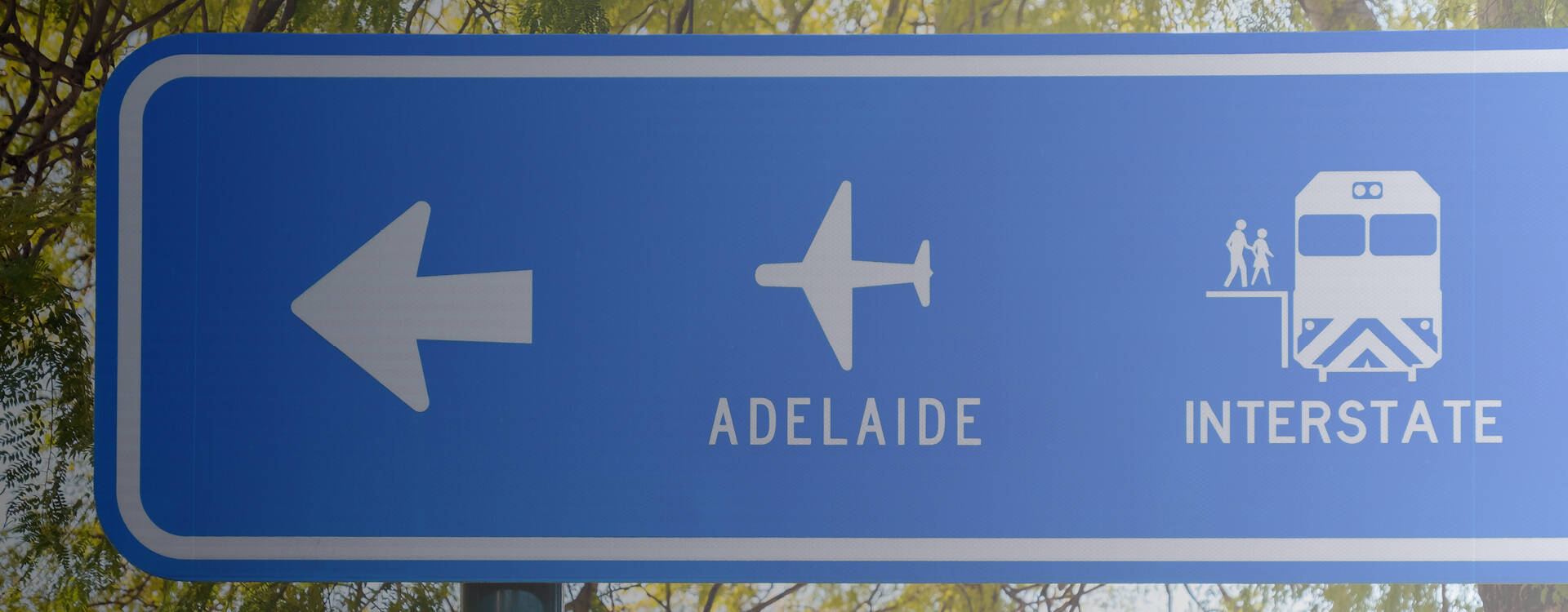 A street sign pointing to Adelaide Airport and the Interstate