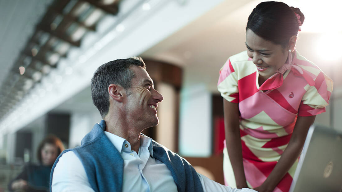 A businessman working on a laptop and speaking to a marhaba representative
