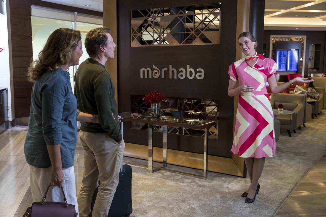 A couple being greeted by a marhaba representative at an airport lounge