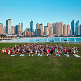 The Jeunesse team talking a picture on a green lawn with the Jeunesse letter laid out in front of them