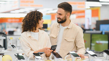 A couple checking out mobiles in an electronics store