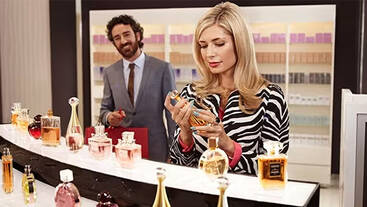 A shop assistant help a woman shop for perfume