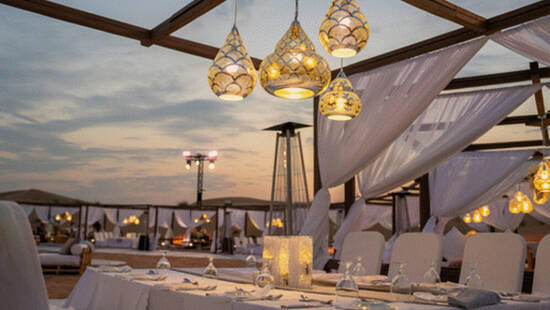 A fancy dining table setup in the desert at sunset