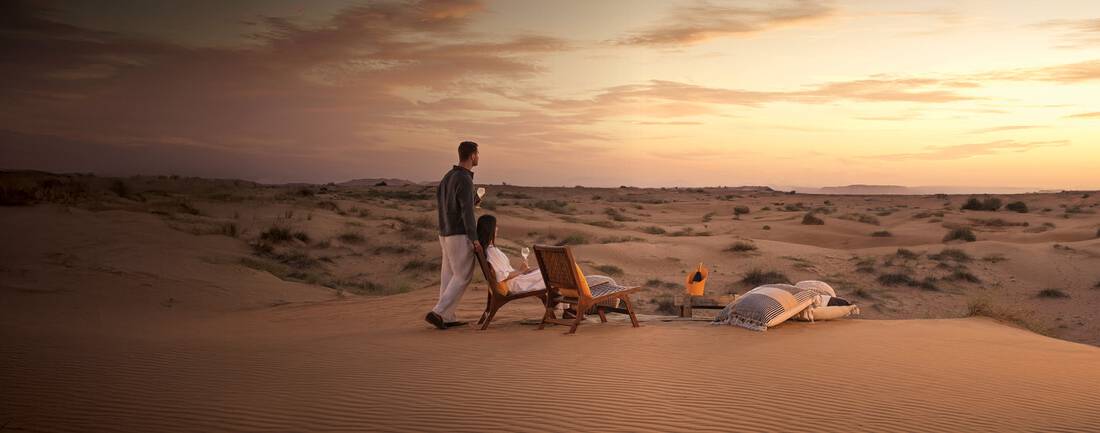 a couple enjoying their drinks in a cozy desert setup