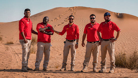 Five Arabian Adventures team members posing for a photo in the desert
