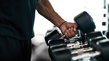 A man wearing black lifting a dumbbell