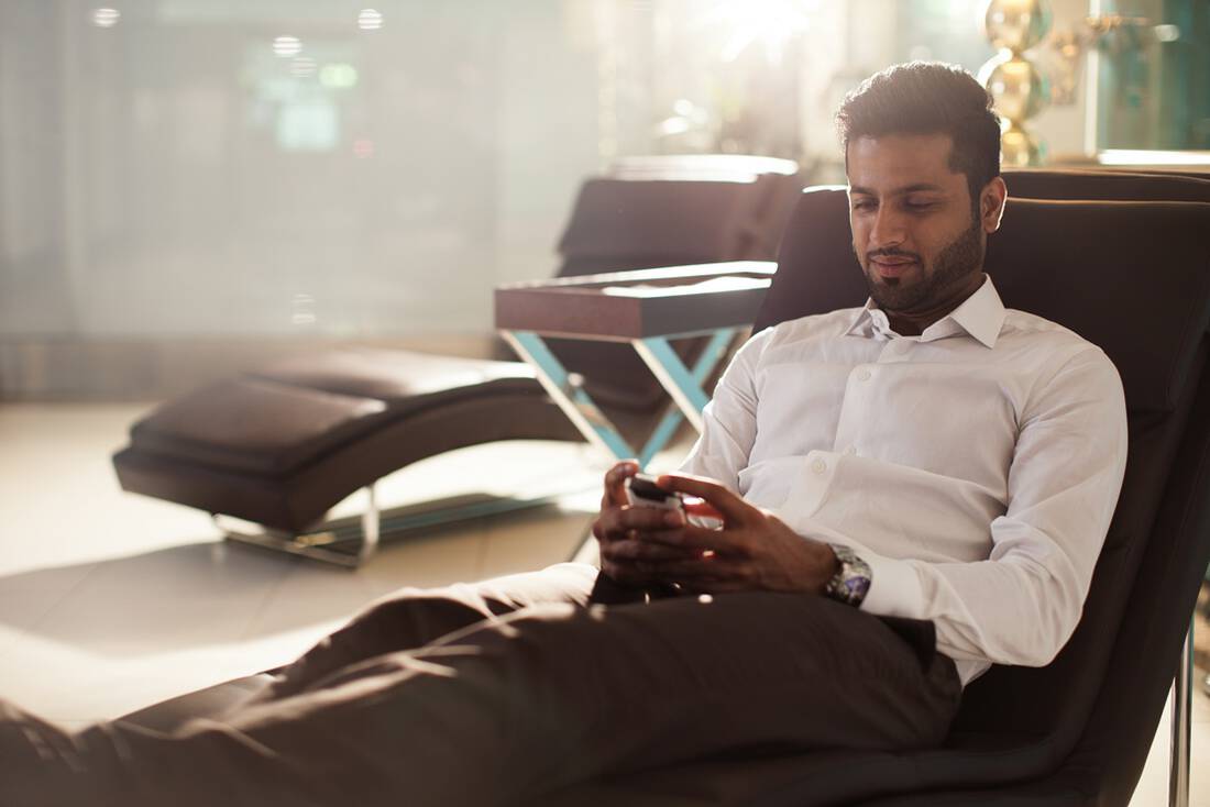 A man sat in a reclining chair using a mobile phone