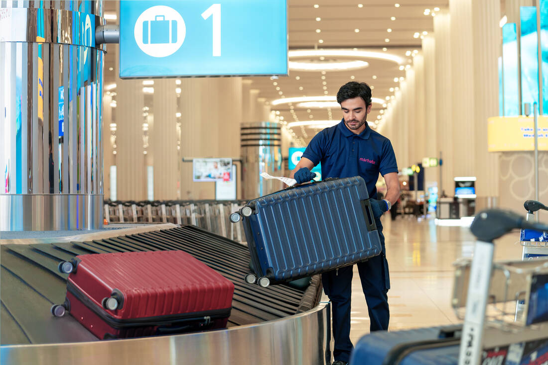 A marhaba team member lifting a bag off the baggage carousel