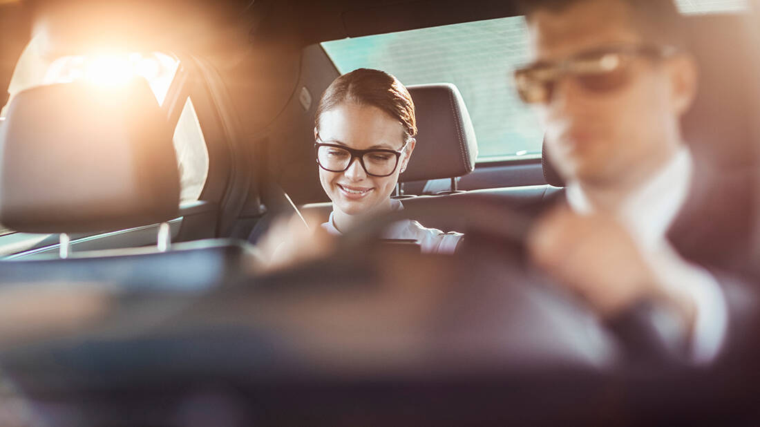 A woman in the back of a chauffeur-driven car