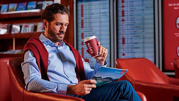 A man enjoying his Costa Coffee while reading a magazine