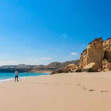 A man walking on a beach in Oman