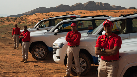 Four certified Arabian Adventures representatives next to their Jeeps