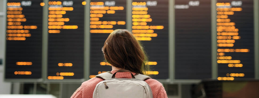 A lady carrying a backpack looking at the flight board