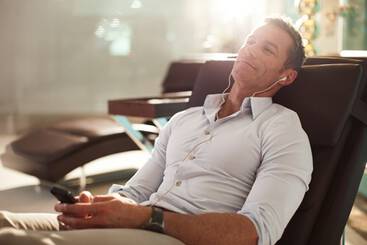 A man sat at an airport lounge with a laptop, speaking to a marhaba team member 