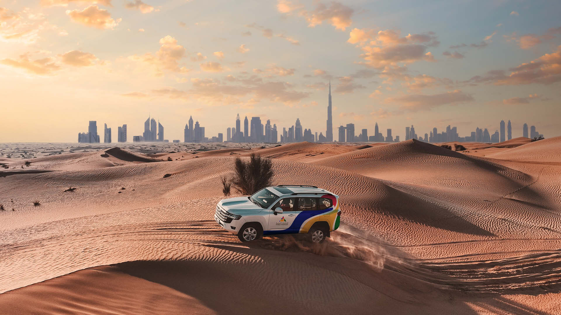 An Arabian Adventures Jeep in the desert at sunset against the Dubai skyline