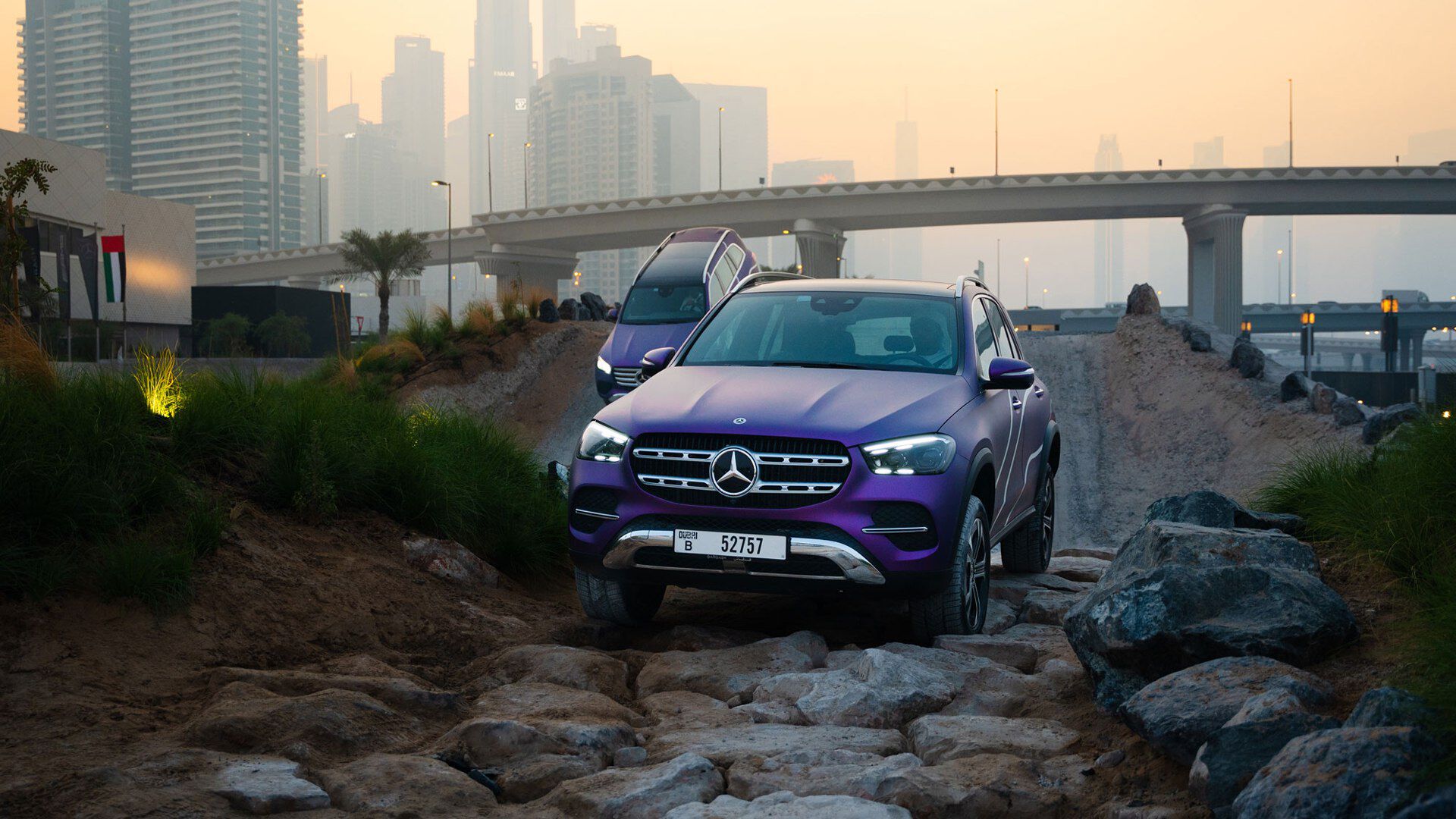 Two purple Mercedes Benz GLEs on an off road track during sunset