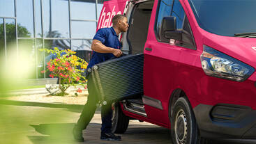 A Check In Anywhere representative loading luggage into a van