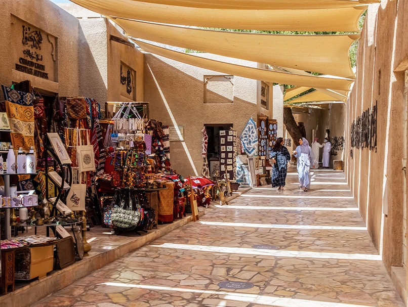 Two women walking past market stalls in Al Fahidi Souk